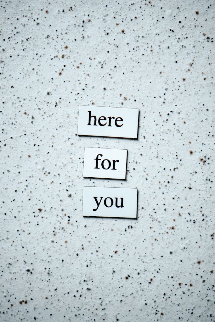 Motivational text 'here for you' on a speckled surface, conveying support.